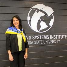 Dr. Vilma Fuentes standing in front of a large LSI logo wall installation. 