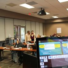 Computer screens showing CPALMS content in the front of a meeting room during a training. 