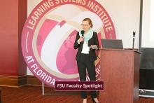 Celia Reddick addressing the LSI staff in front of a large round LSI logo banner.