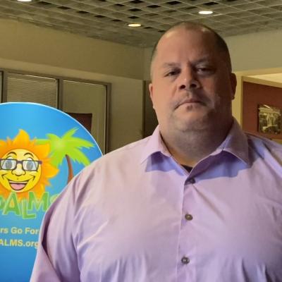 Screenshot of a teacher being interviewed in front of a circular CPALMS banner.