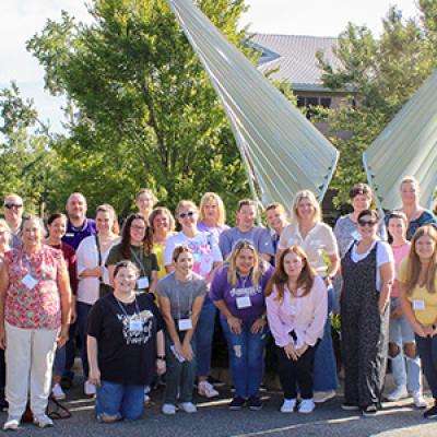 Group photo of teachers in front of a sculpture at the FSU Aero-Propulsion, Mechatronics, and Energy building. 