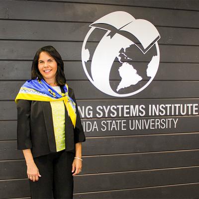Photo of Dr. Vilma Fuentes standing next to an LSI wall logo. 