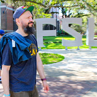 DakhaBrakha's Marko Halanevych walking past a large FSU installation of campus. 