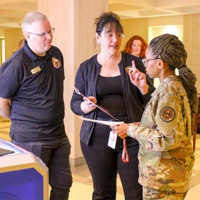 Jim Reynolds and Carrie Meyers in discussion with a women in military camos. 