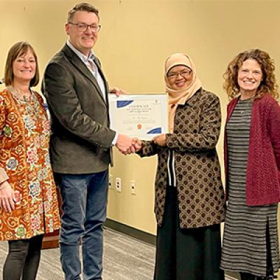 Dr. Ely Djulia Katmadihardja receiving a certificate from three representatives from Columbus State University.