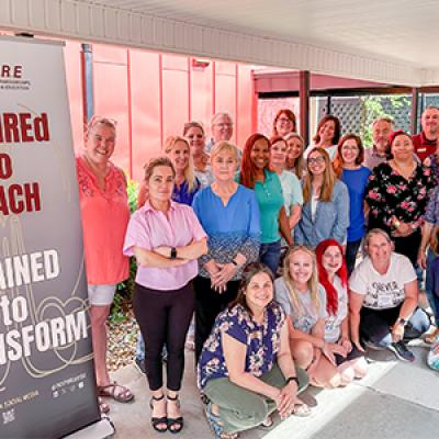 Group photo of participants in the FSU InSPIRE summer teacher workshops posing next to a stand-up banner. 