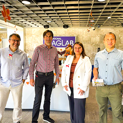 Four people posing for a photo at FSU's Mag Lab.