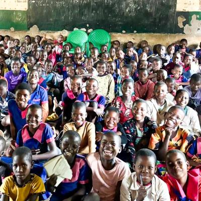 Classroom of students in Malawi sitting on the floor.