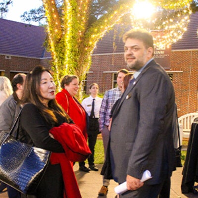 Photo of Rabieh Razzouk outdoors speaking with a woman at an LSI banquet.