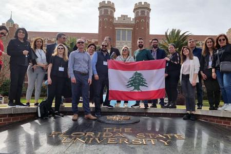 Group of visitors from Lebanon posing with the Lebanese flag in front of FSU's Westcott Building