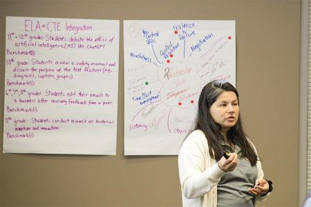 Zaida McGinley presenting in front of large sheets of paper affixed to a wall.