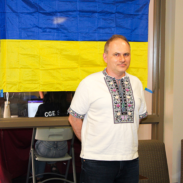 "Dr. Tara Panchenko posing in front of a Ukrainian flag"