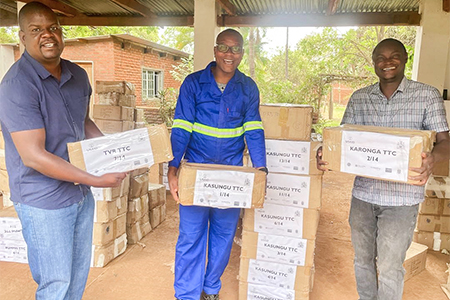"Three men in Malawi carrying boxes of books."