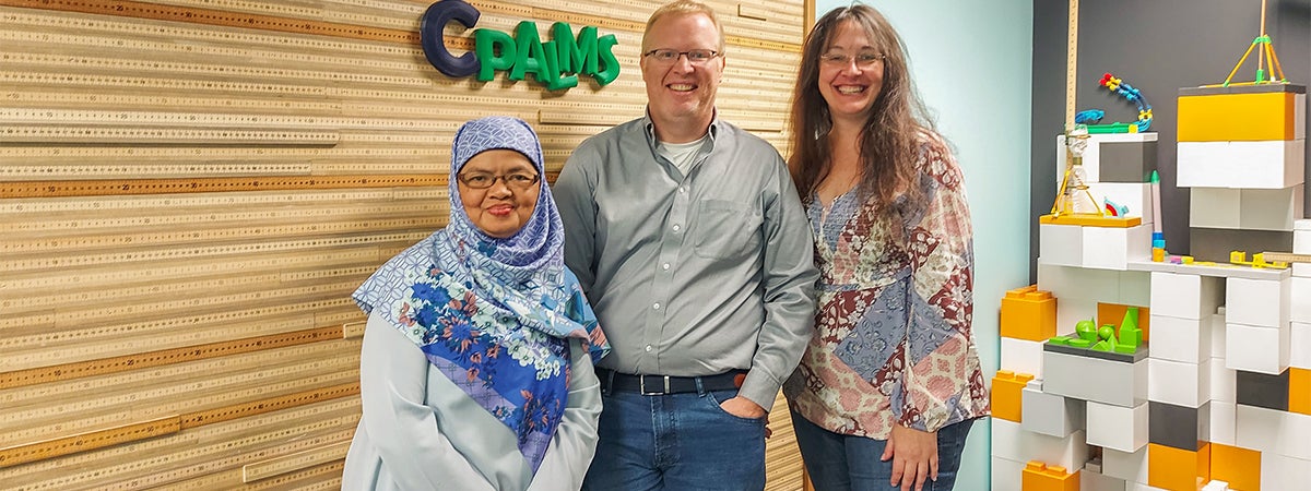 "Dr. Djulia with LSI faculty members Carrie Meyers and Jim Reynolds in front of a CPALMS wall sign."